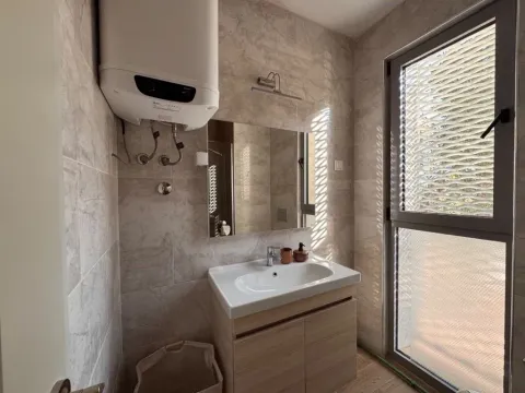 Modernly equipped bathroom with a washbasin, mirror, and water heater. - image 11