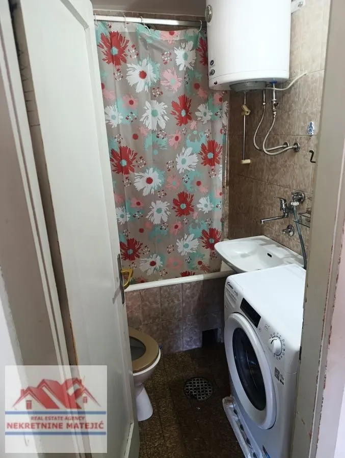 Small bathroom with a bathtub, washbasin, washing machine, and water heater.