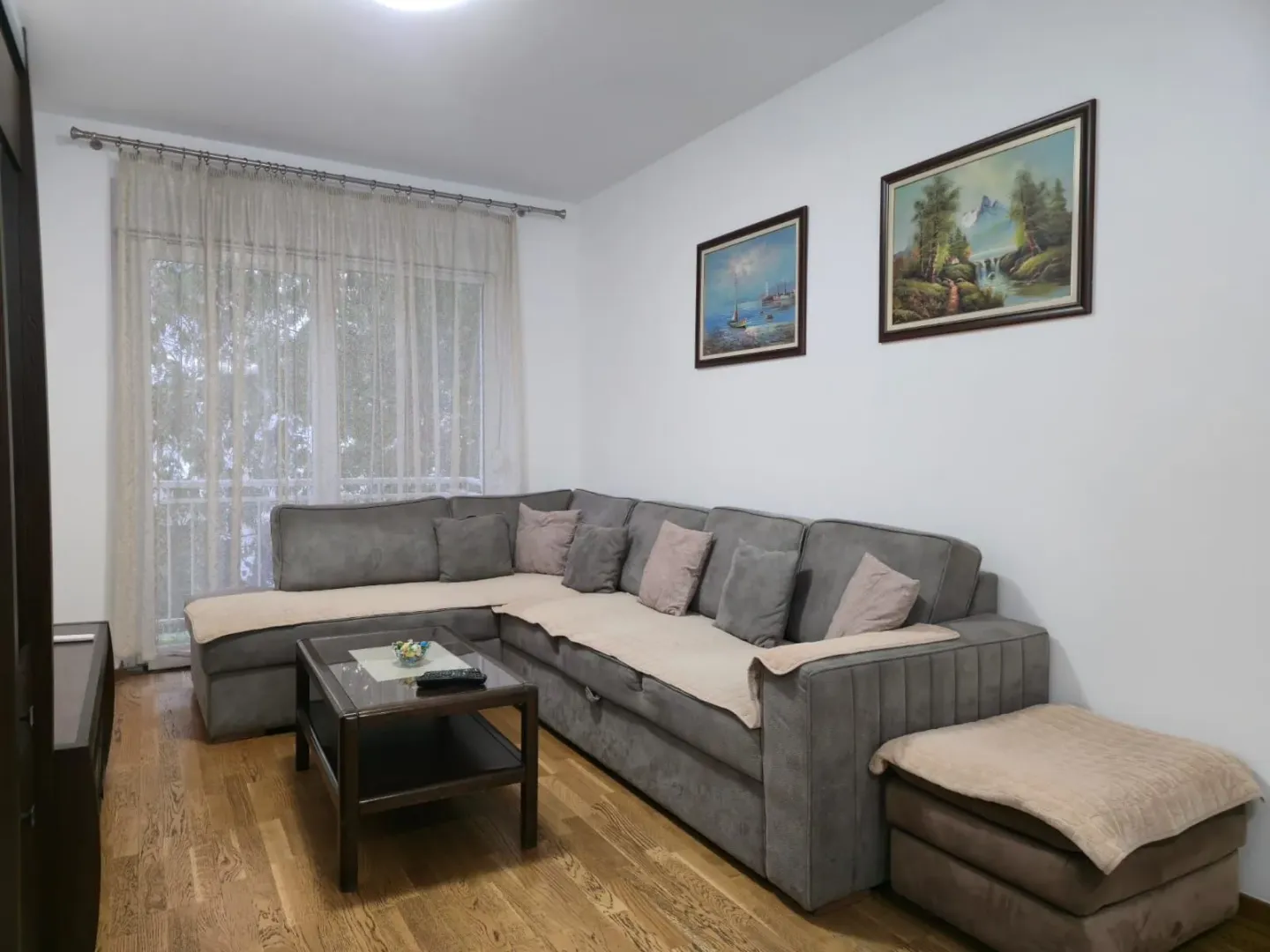 Living room with a sectional sofa, coffee table, and paintings on the wall.