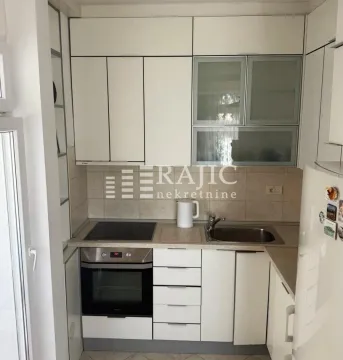 Smaller equipped kitchen with white cabinets and a built-in oven. - image 6