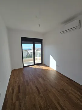 Prazna soba sa drvenim podom, klima uređajem i balkonskim vratima. - image 14