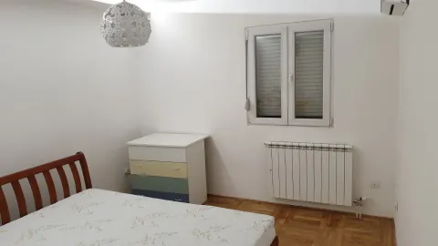 A simply furnished bedroom with a wooden bed and a chest of drawers. - image 11