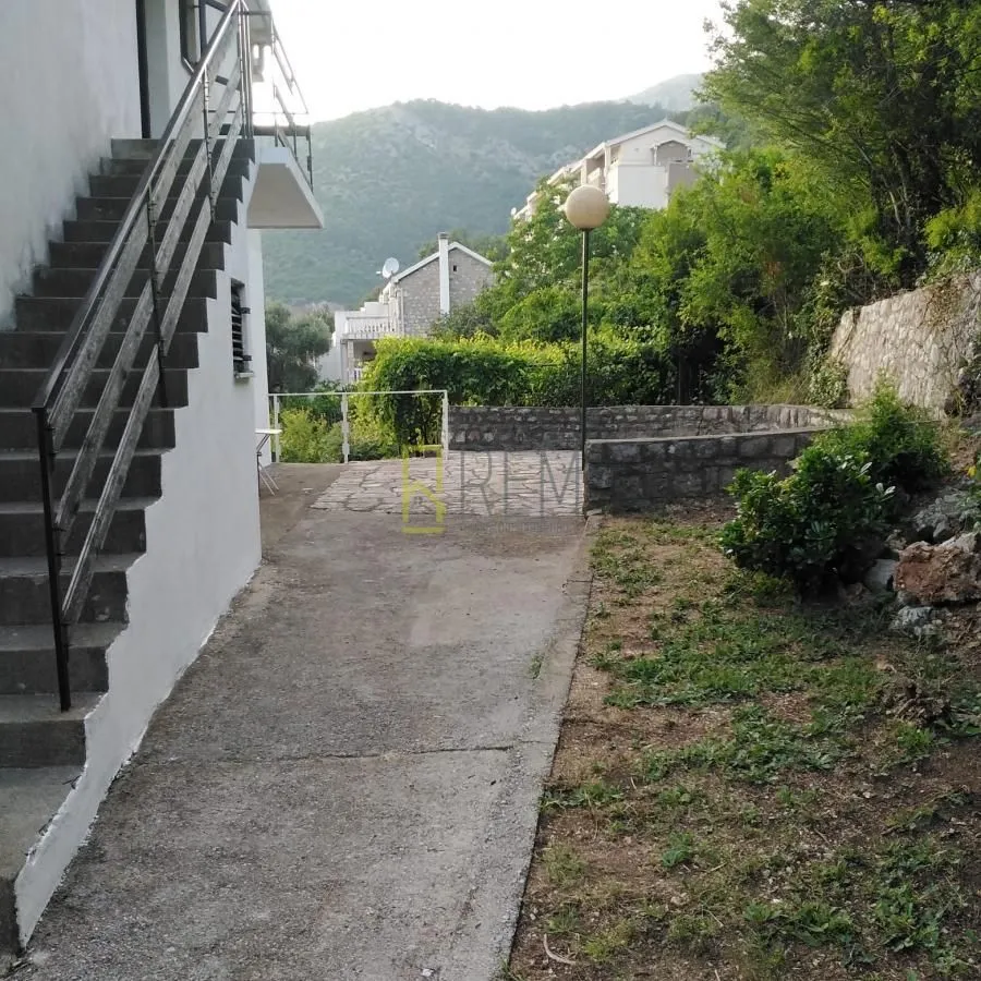 Eksterijer kuće sa dvorištem i spoljnim stepeništem.