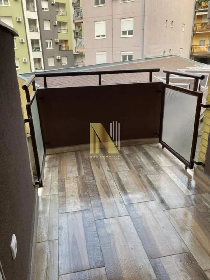Nenamešten balkon sa keramičkim pločicama na podu i metalnom ogradom.