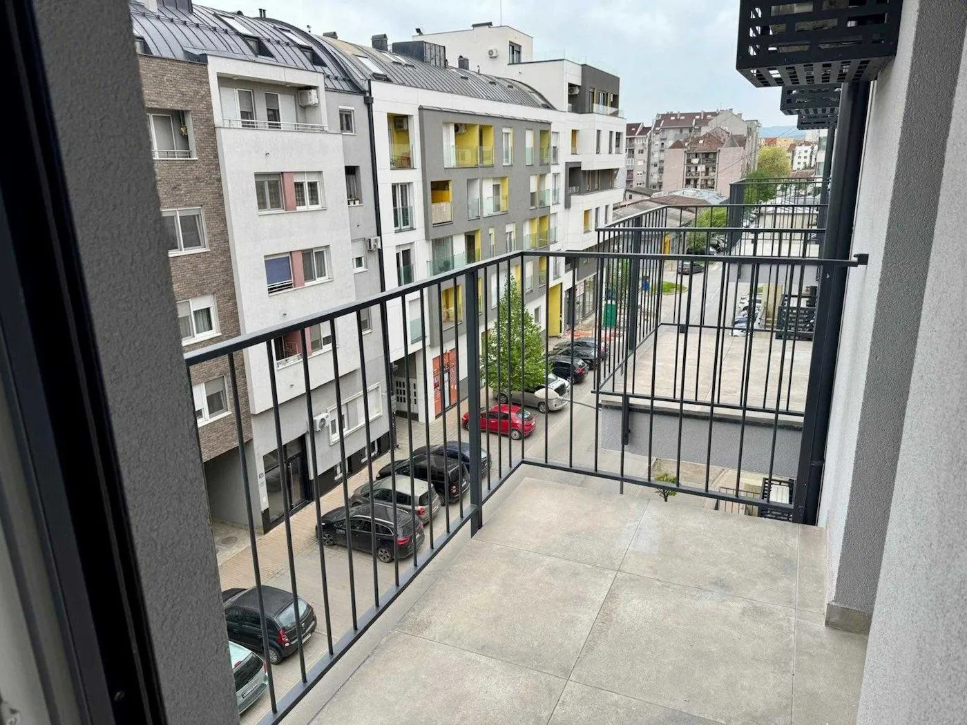 Pogled sa balkona na gradsku ulicu i okolne zgrade.