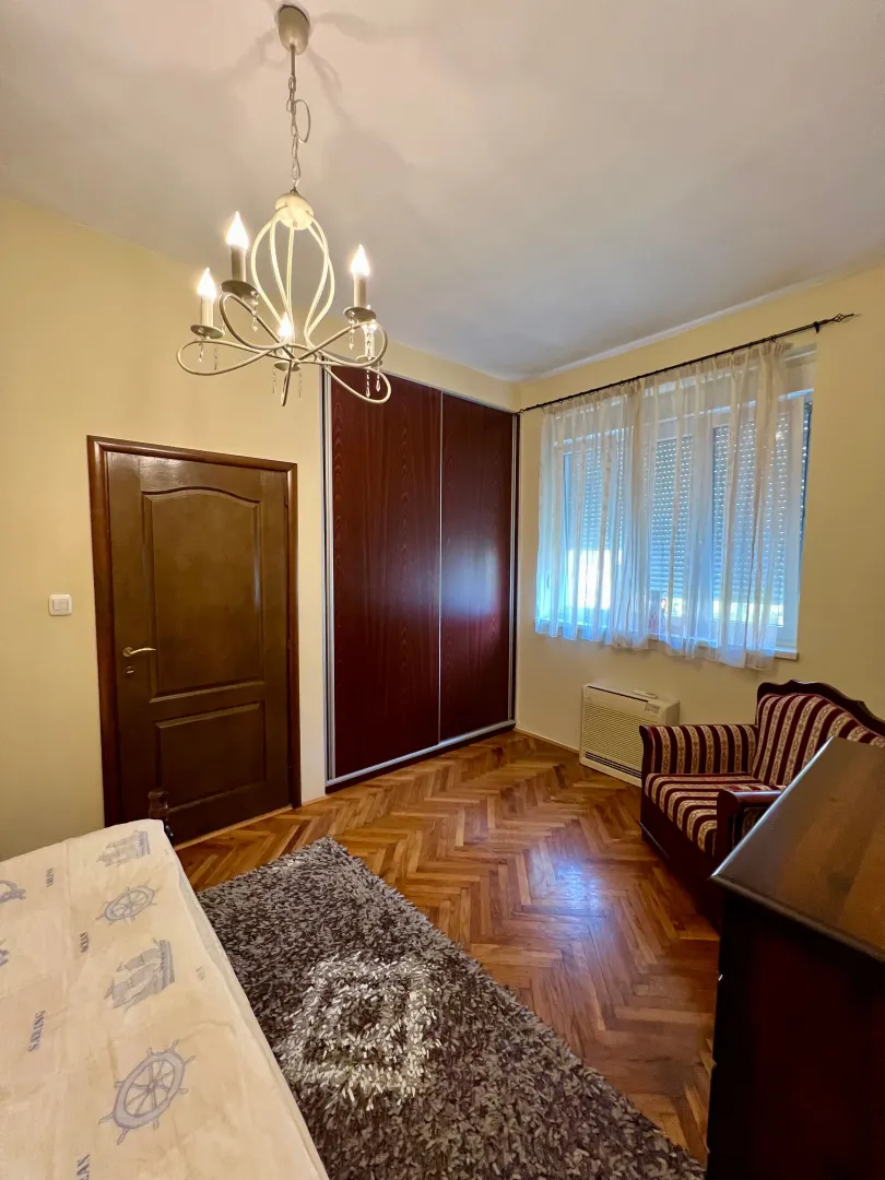 Furnished bedroom with a bed, wardrobe, and parquet flooring.