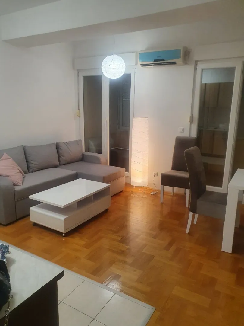 Bright living room with a grey corner sofa and parquet flooring.