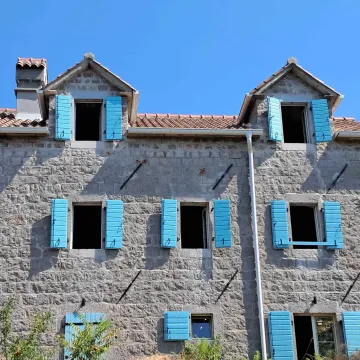 Stone house facade with blue window shutters. - image 23