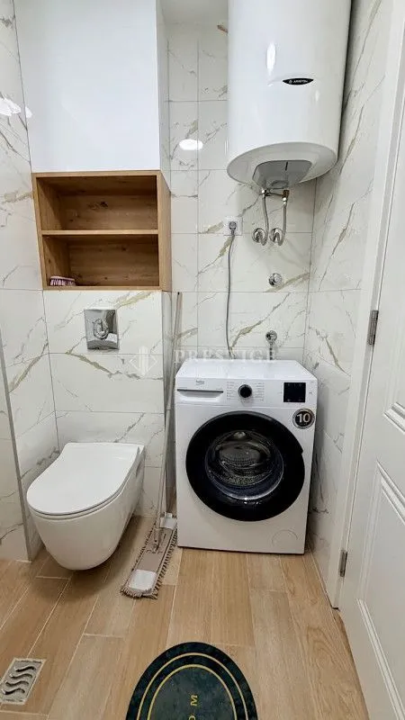 Moderno opremljeno kupatilo sa veš mašinom i ugradnim wc šoljom.