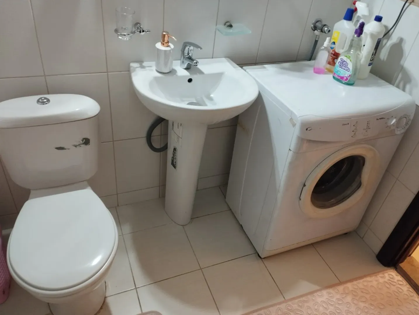 Jednostavno kupatilo sa toaletom, umivaonikom i veš mašinom.