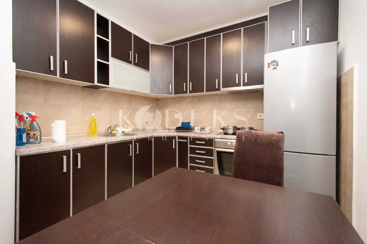 Dark wood kitchen cabinetry with a dining table and a refrigerator.