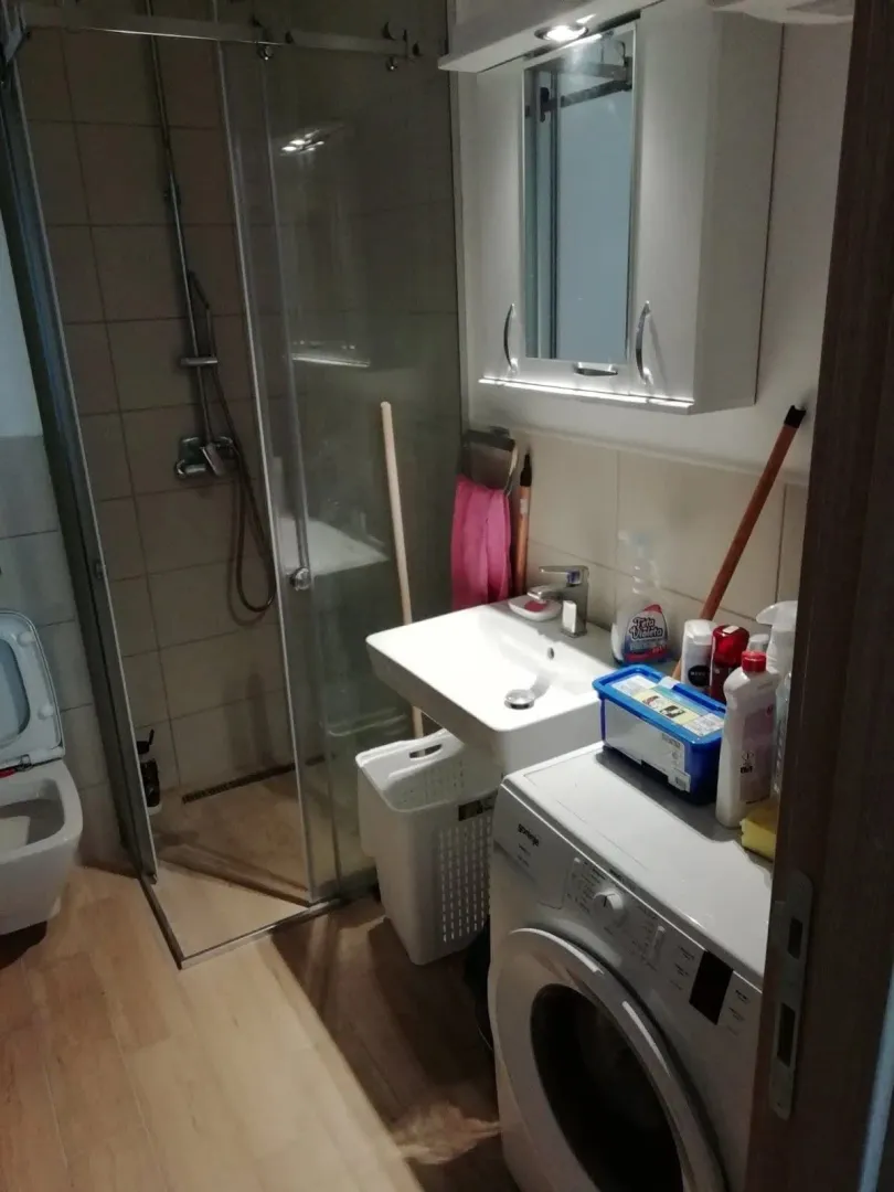 Manje kupatilo sa tuš kabinom, umivaonikom i veš mašinom.