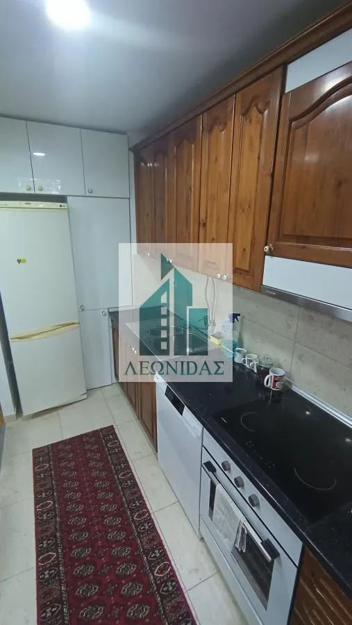 Kitchen with wooden cabinetry, refrigerator, and built-in oven.
