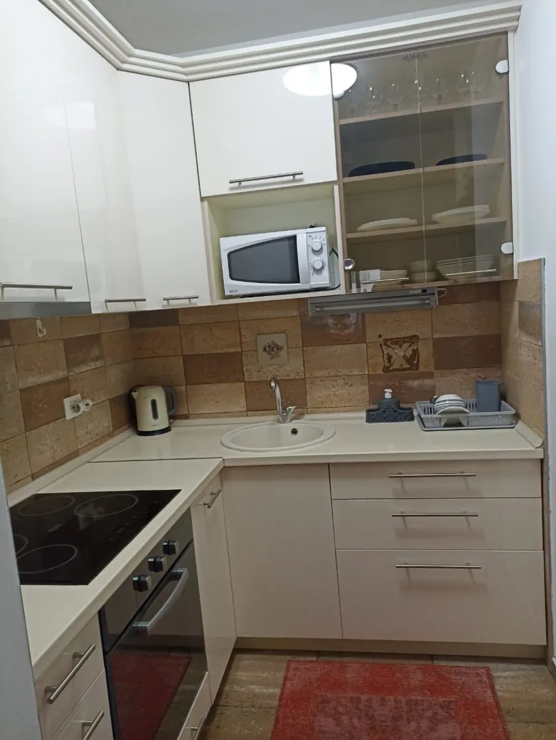Small kitchen with light cabinets, built-in oven and sink.