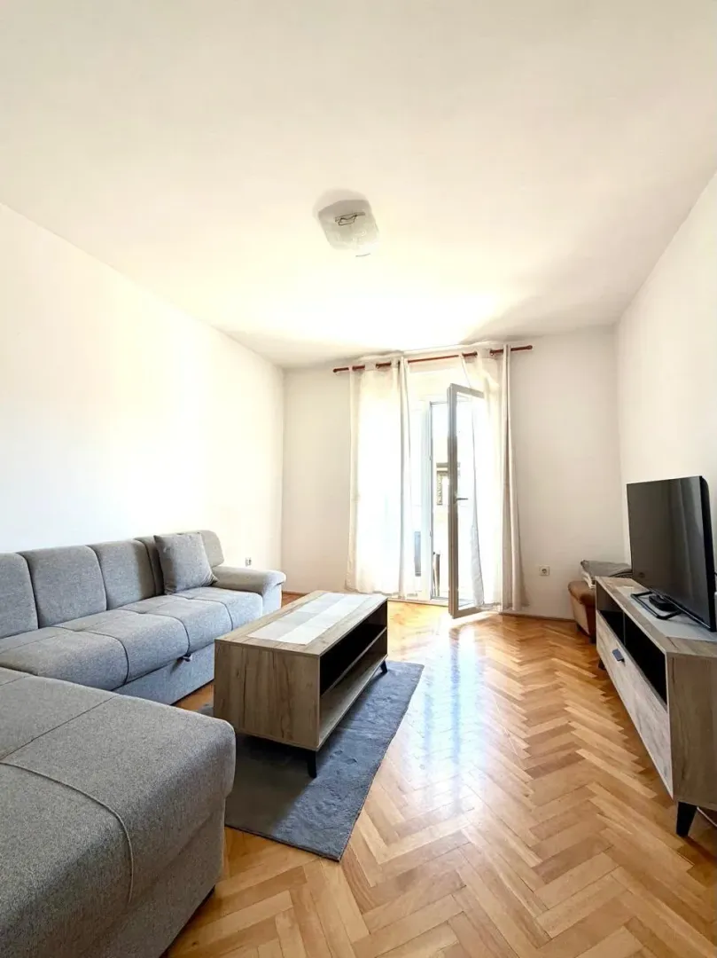 Bright living room with a sofa, TV unit, and access to the terrace.