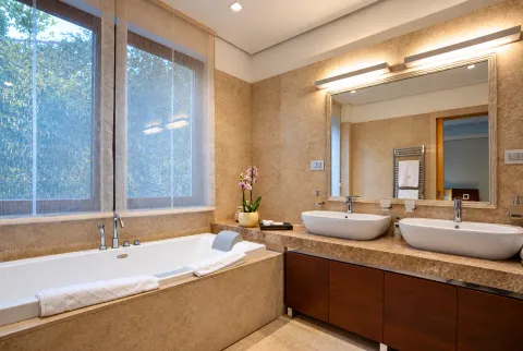 Spacious bathroom with a bathtub, large window, and double vanity. - image 10