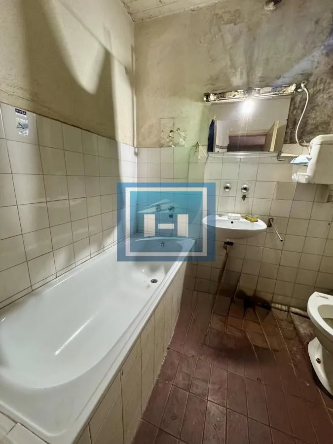 Starije kupatilo sa kadom, umivaonikom i toaletom.