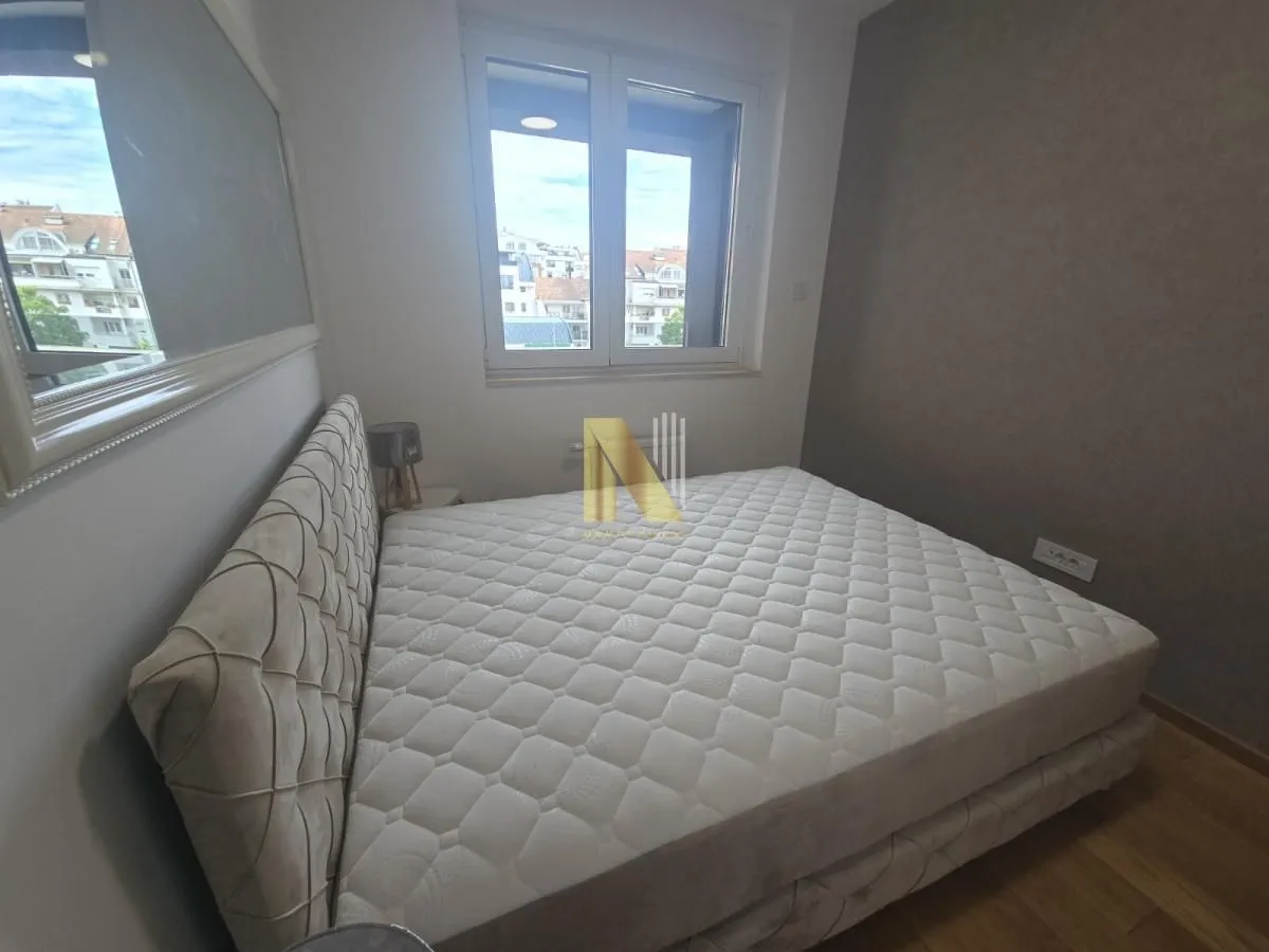 Spavaća soba sa velikim bračnim krevetom i prozorom.
