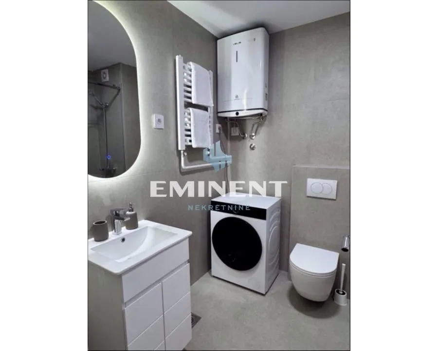 Modern bathroom equipped with sanitary ware, a shower cabin, and a washing machine.