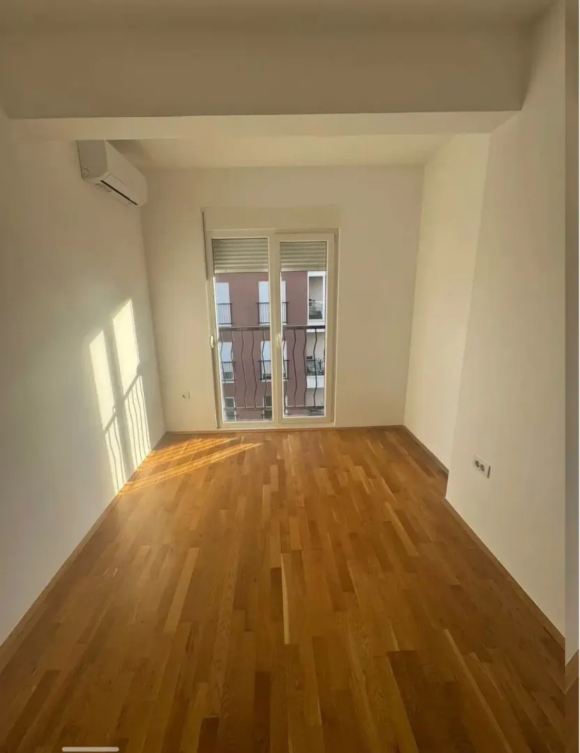 Empty room with parquet flooring and an air conditioner.