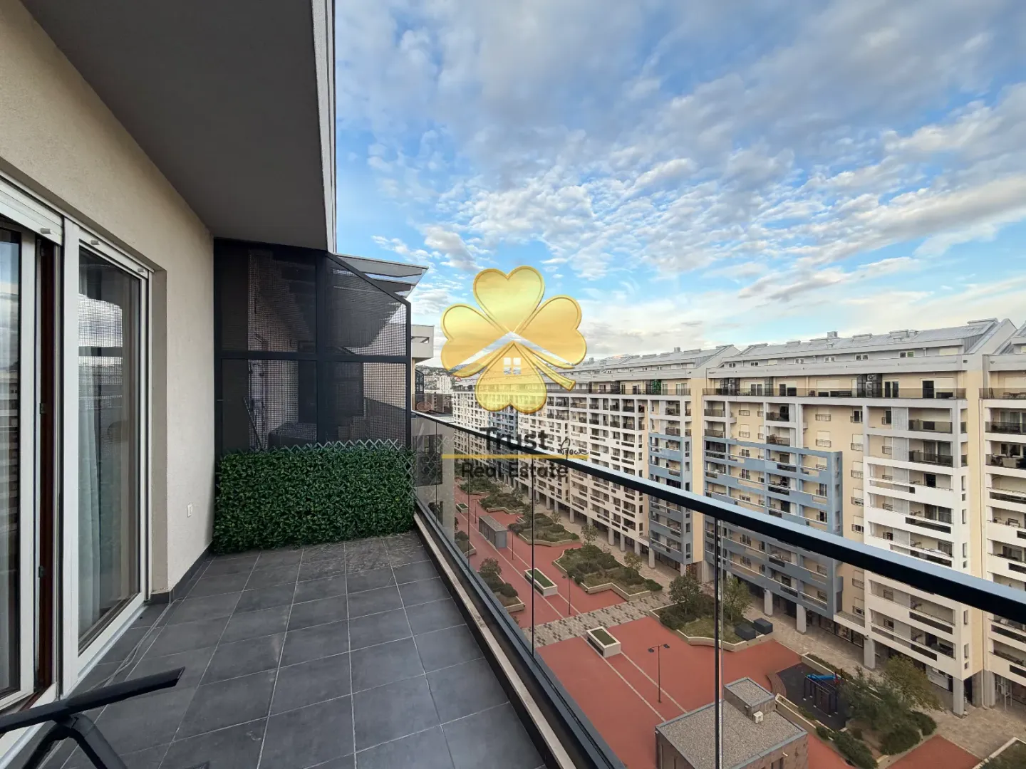 Spacious balcony with a view of the neighborhood and residential buildings.