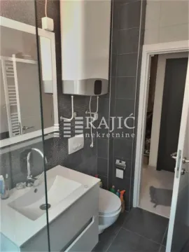 Modernly equipped bathroom with a washbasin, toilet bowl, and water heater. - image 15