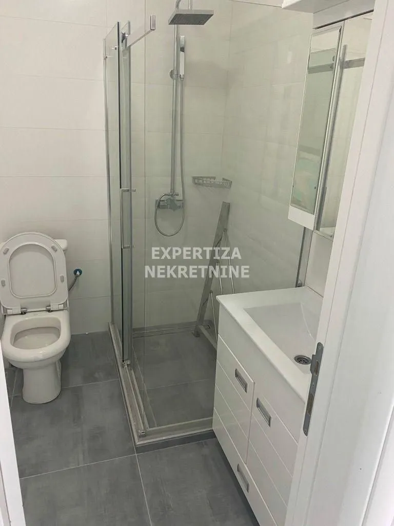 Smaller bathroom with a shower cabin, washbasin, and toilet.