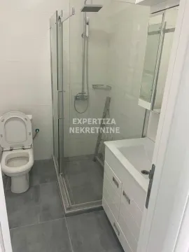 Smaller bathroom with a shower cabin, washbasin, and toilet. - image 4