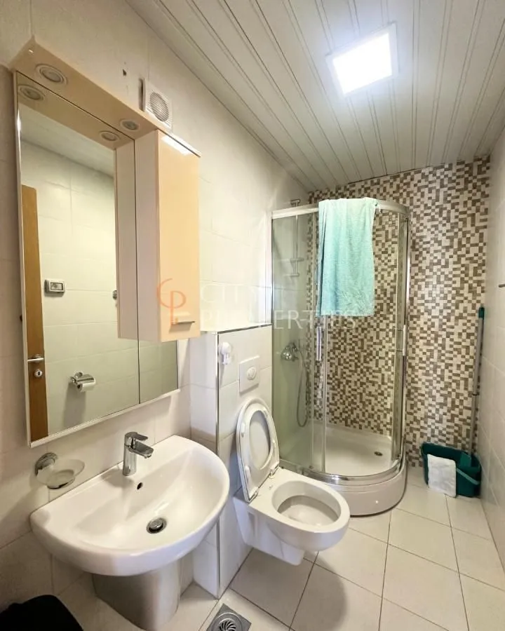 Kupatilo opremljeno umivaonikom, WC šoljom i tuš kabinom.