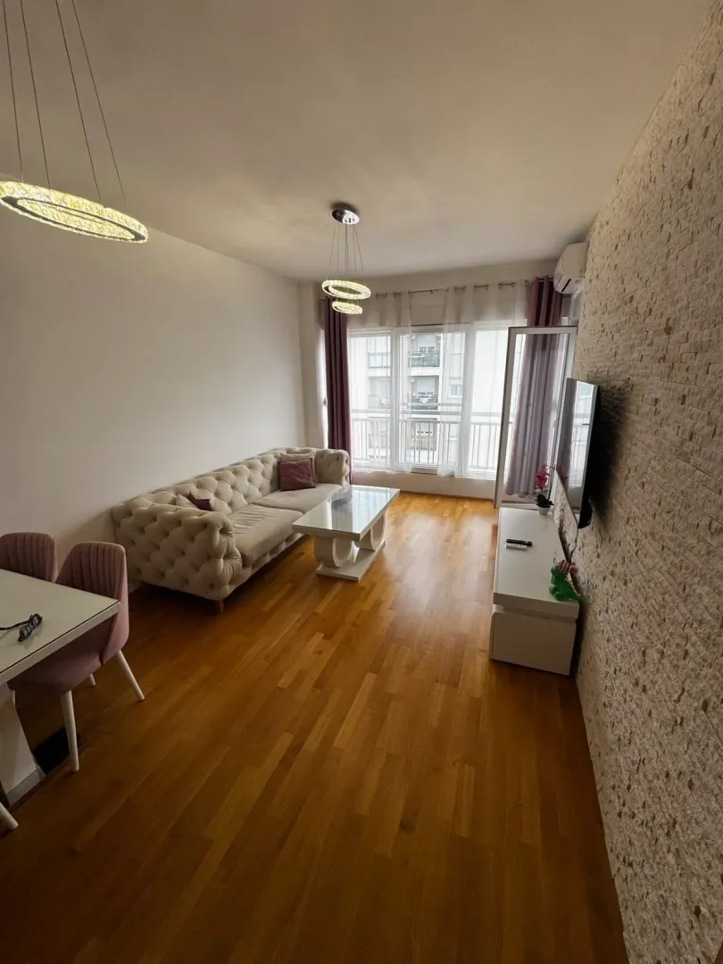 Living room with sofa, dining table, and TV unit.