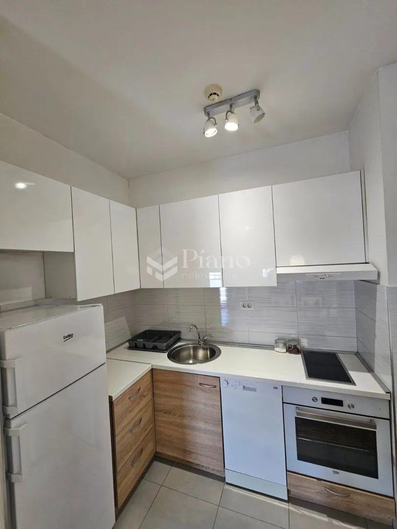 Small kitchen with white cabinets, refrigerator, and built-in appliances.