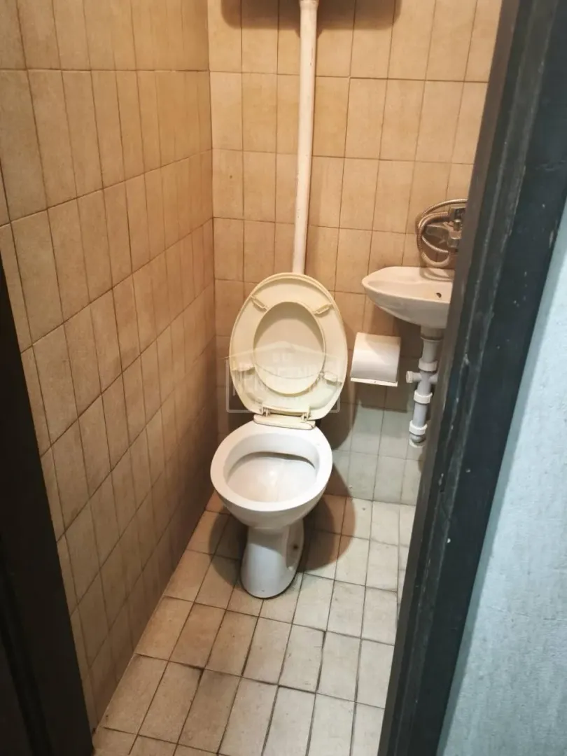 Small bathroom with a toilet and a sink, tiled with ceramic tiles.