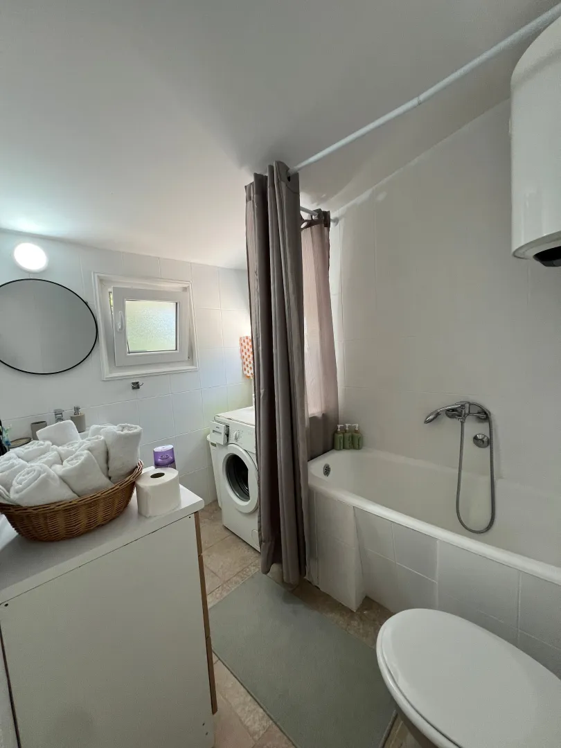 Small bathroom with a bathtub, sink, and washing machine.