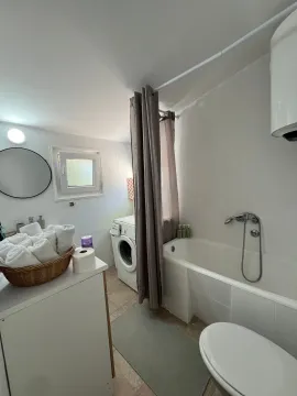 Small bathroom with a bathtub, sink, and washing machine. - image 7