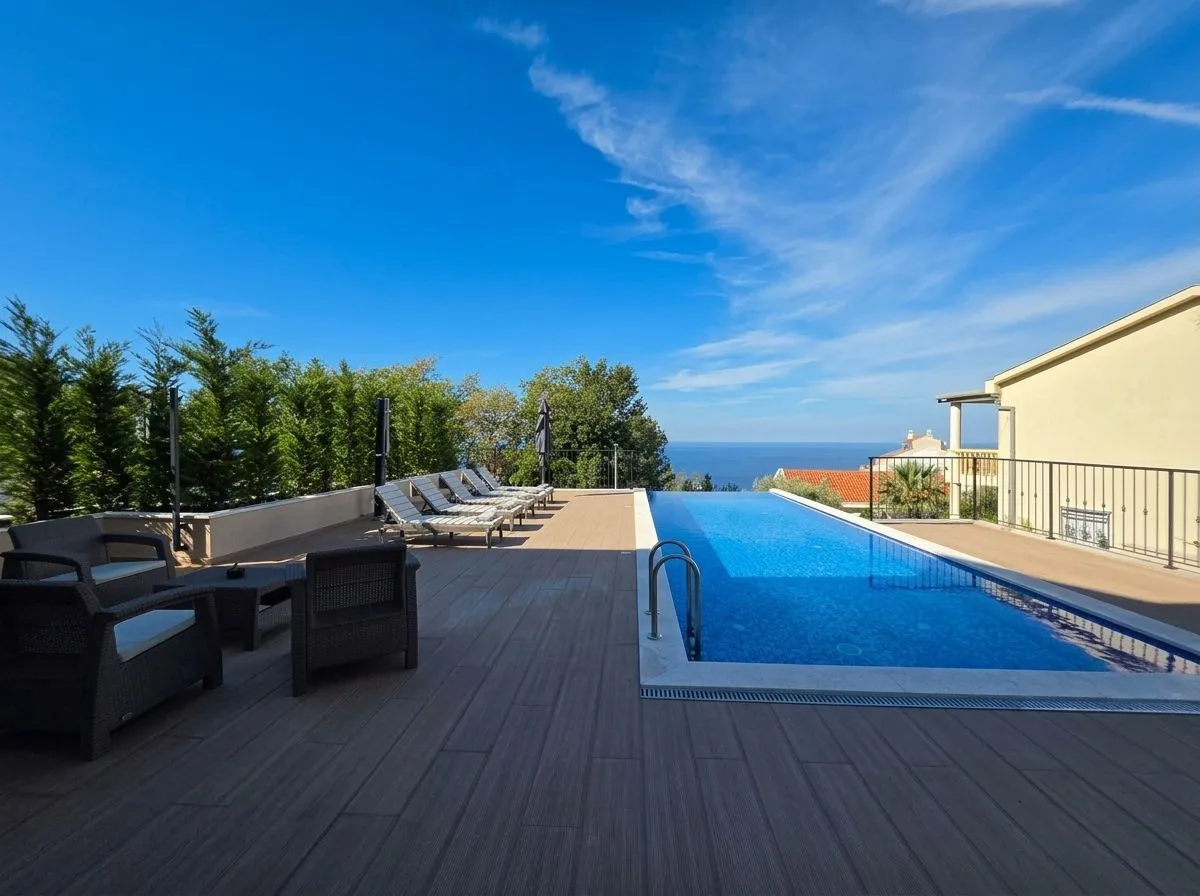 Terrace with a swimming pool, sun loungers, and seating area with a sea view.