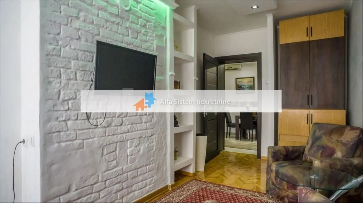 Living room with a white brick wall, television, and a view towards the dining area.