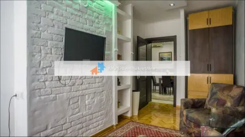 Living room with a white brick wall, television, and a view towards the dining area. - image 5
