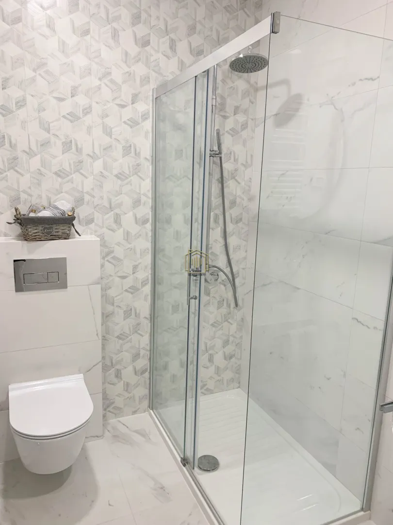 Moderno opremljeno kupatilo sa tuš kabinom i ugradnom šoljom.