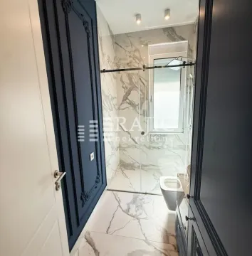 Modern bathroom with marble tiles and a walk-in shower. - image 14