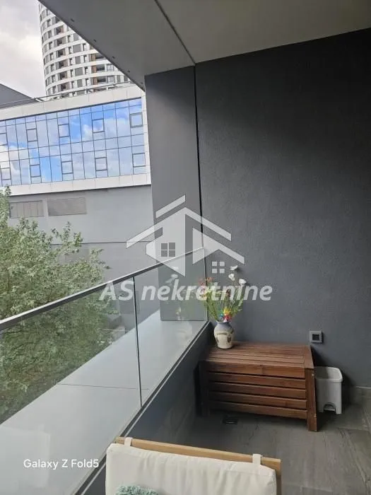 Covered balcony with a glass railing and city view.