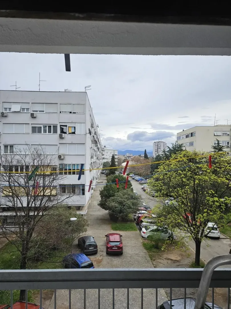 View from the balcony overlooking surrounding residential buildings and parking lot.