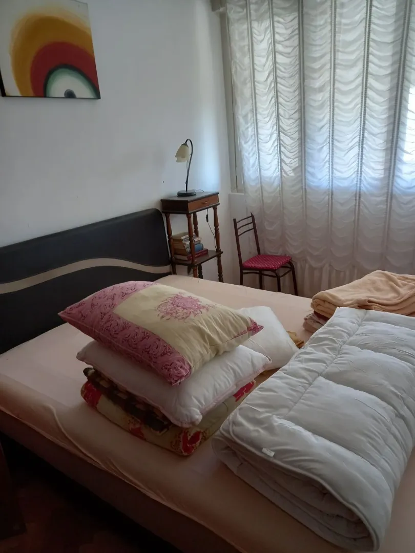 Jednostavna spavaća soba sa bračnim krevetom i noćnim stolićem.