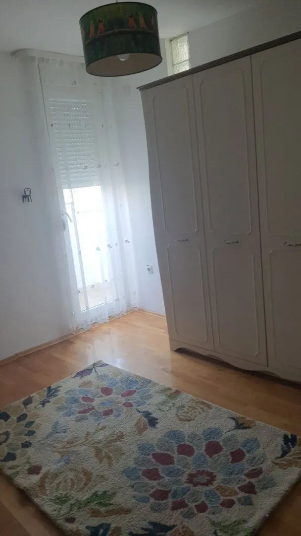 A bright room with a large wardrobe, a colorful rug, and balcony access.