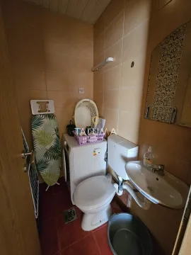 Small bathroom with a toilet, washbasin, and washing machine. - image 10