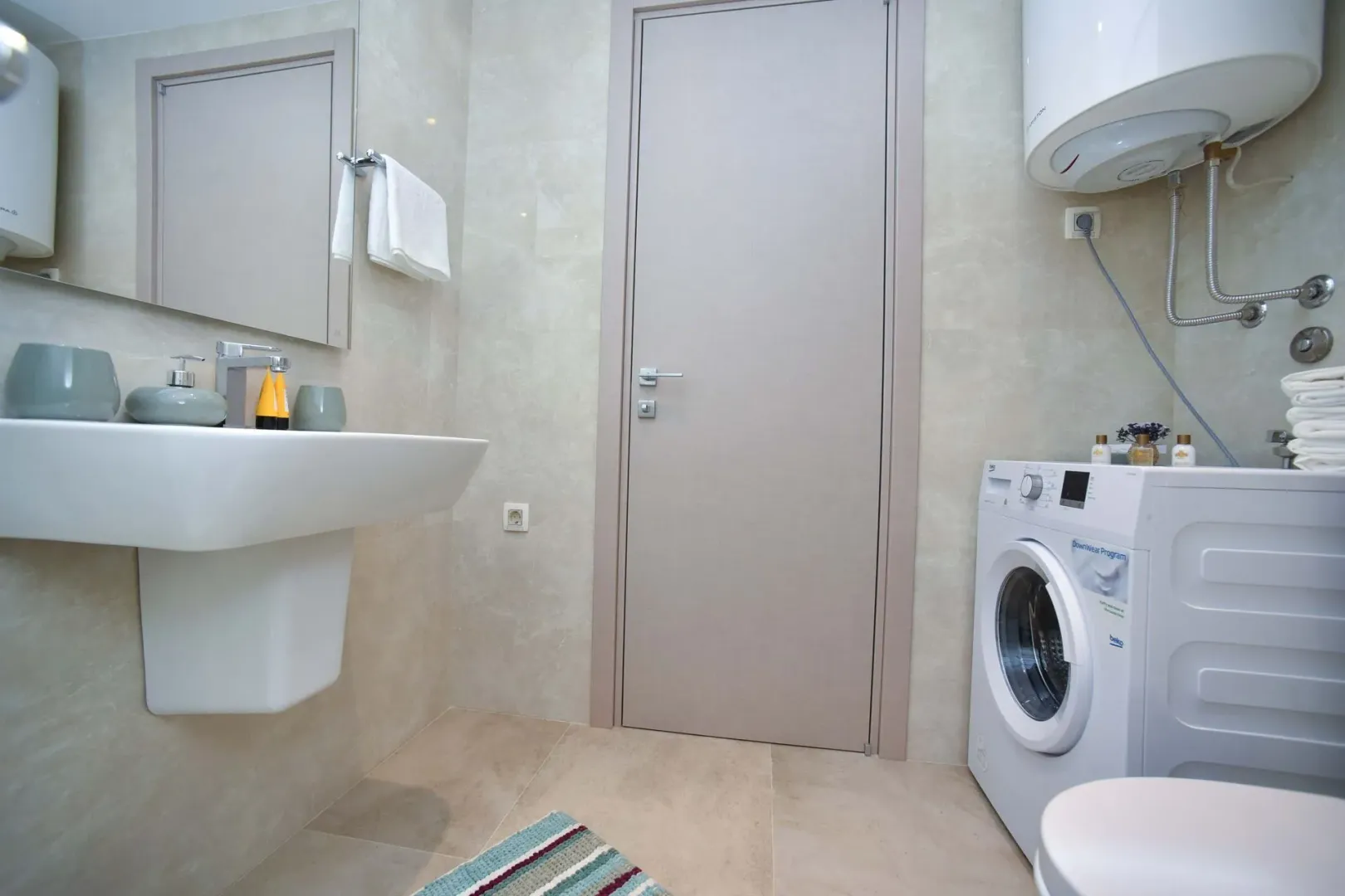 Bathroom with sink, mirror, door, and washing machine.