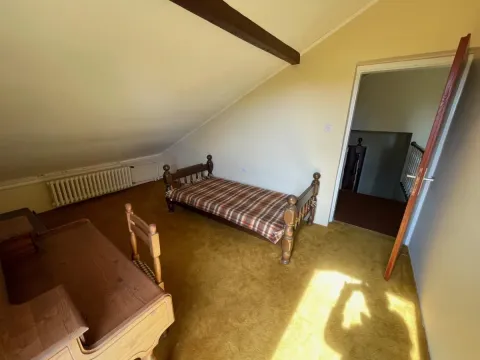 Potkrovlje opremljeno krevetom, drvenim stolom i krovnim kosinama. - image 31