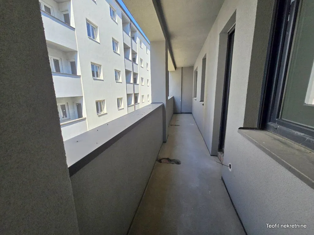 Dugačak nenamesten balkon sa pogledom na susednu zgradu.