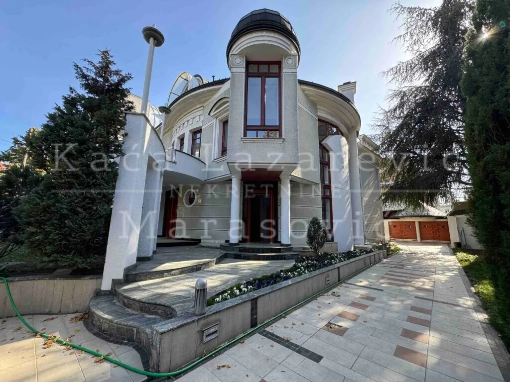 Front view of the house with a paved courtyard and landscaped garden.