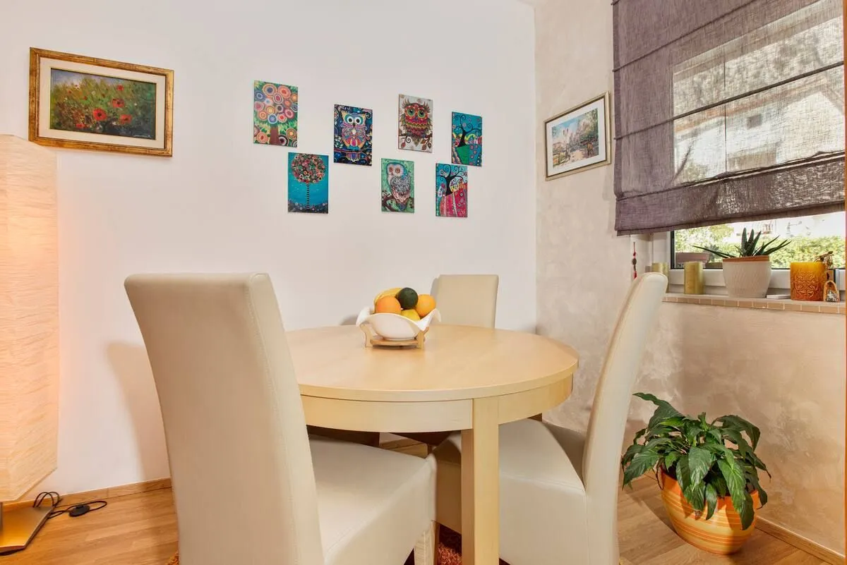 Dining area with a round table and chairs, decorated with artwork on the wall.