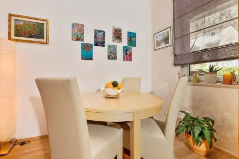 Dining area with a round table and chairs, decorated with artwork on the wall. - image 12